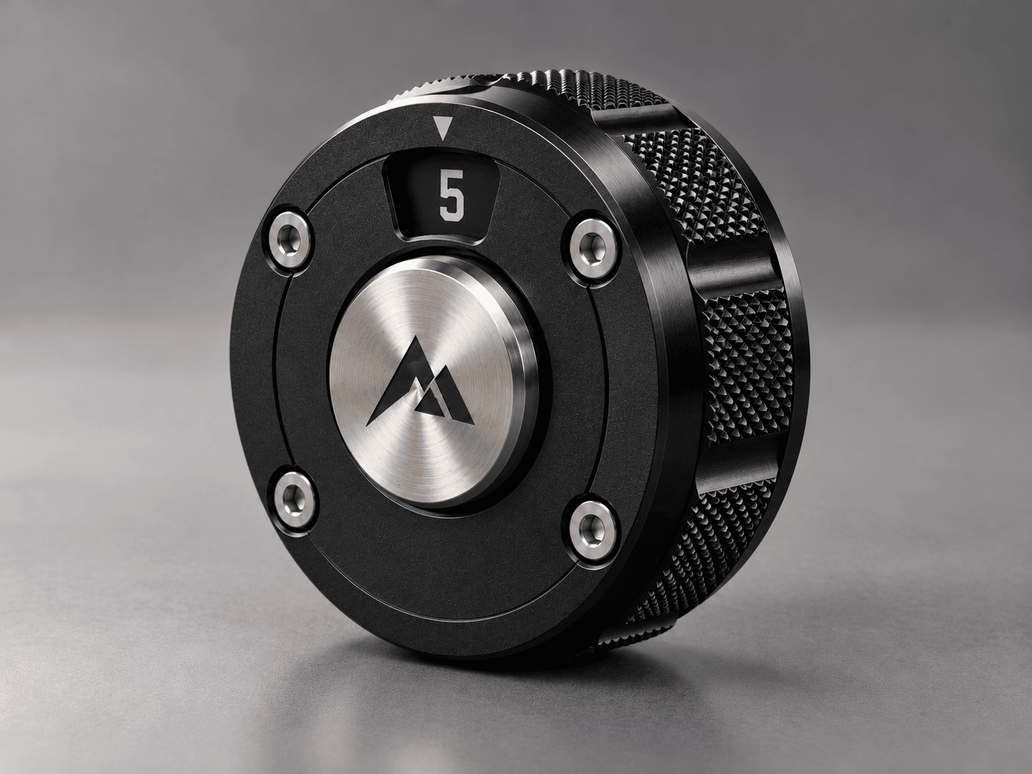 Concept rendering of The Dial: a black anodized puck with a finely knurled outer ring, a single number window showing 5, and a fixed brushed-steel center medallion.